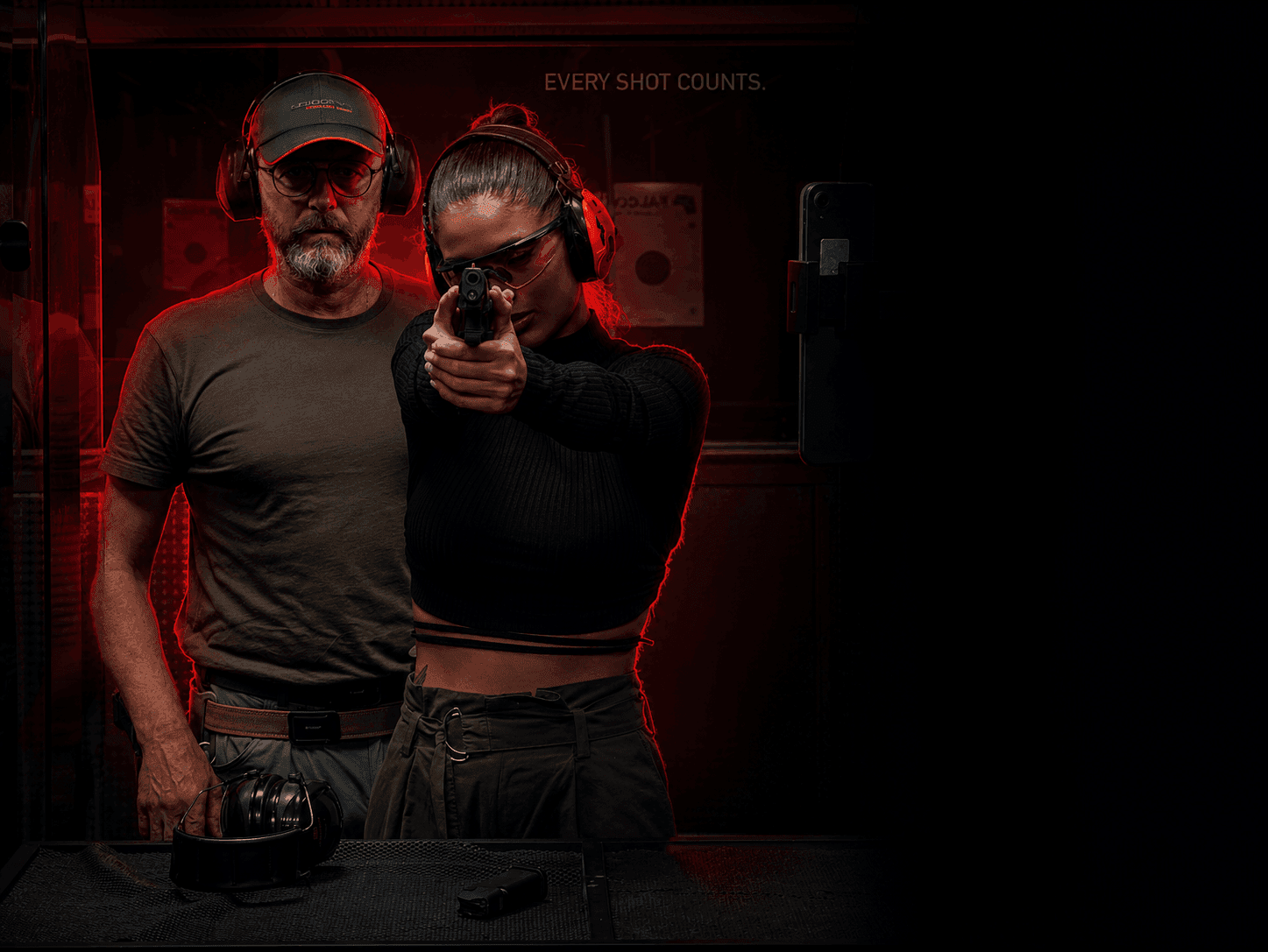 A shooting coach guiding a trainee at the range